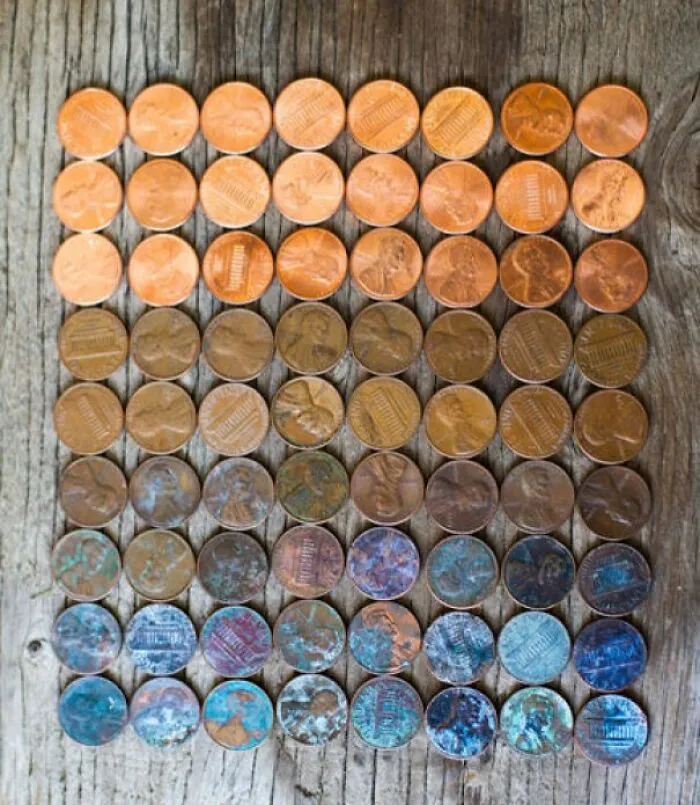 Coins arranged by color transformation over time on wooden surface.