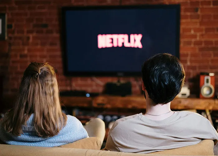 Two people watching Netflix in a cozy living room, reminiscing about life without social media.