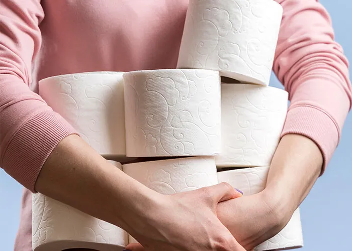 Person holding multiple toilet paper rolls in pink sweatshirt, highlighting unserious brand boycotts.