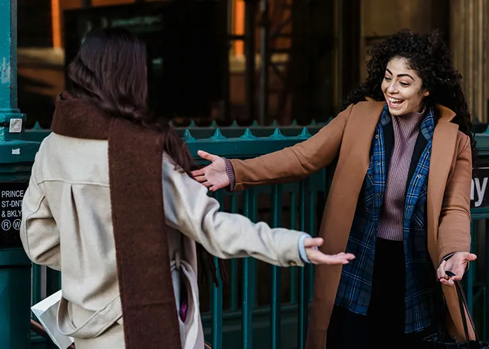 Two women embracing joyfully at a subway entrance, capturing life without social media.