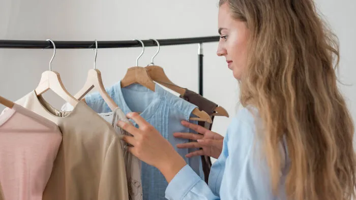 A woman appreciating vintage fashion habits, choosing clothes from a rack.