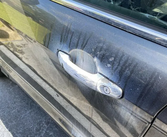 Car door shows signs of wear with streaks of grime on the surface.
