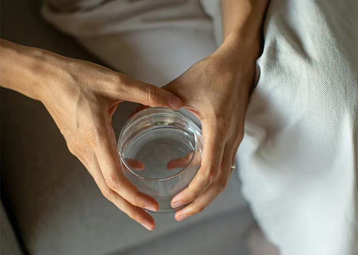 Person holding a glass of water, representing diet choices and experiences.