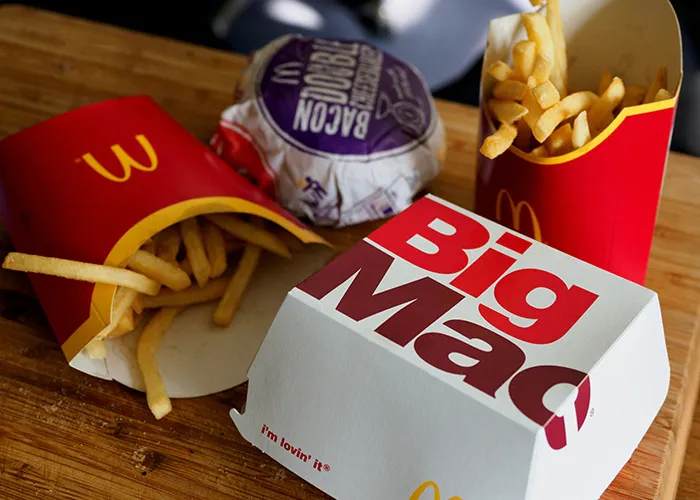 Fast food meal on a table, including fries, a burger, and a Big Mac box, illustrating unhealthy diet choices.