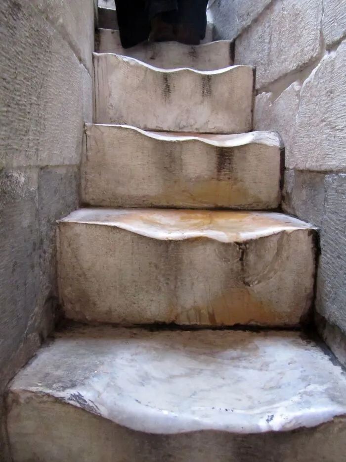Worn stone steps transformed by time and use, showing deep indentations and a textured surface.