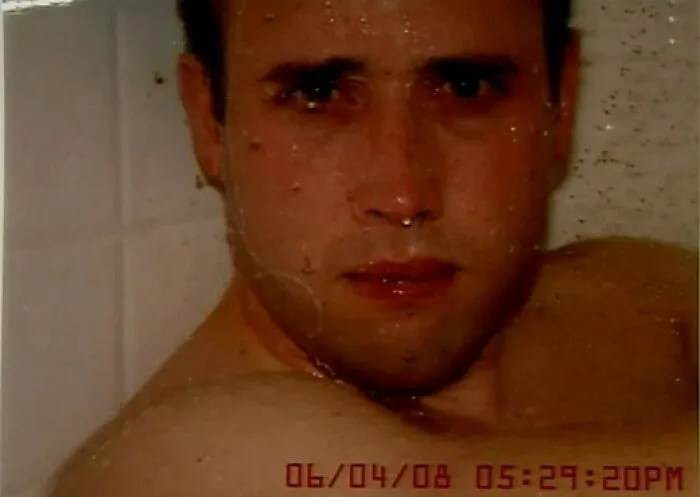 Man in a bathtub staring at the camera, timestamp overlay suggesting a dark history.