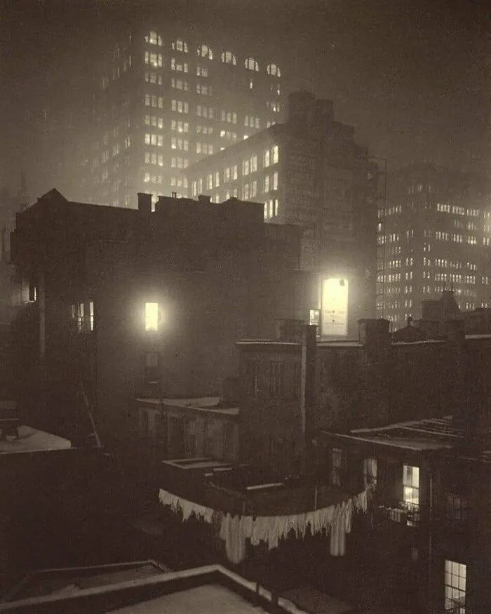 Historical cityscape at night, showcasing illuminated buildings and laundry hanging on a clothesline, evoking nostalgia.