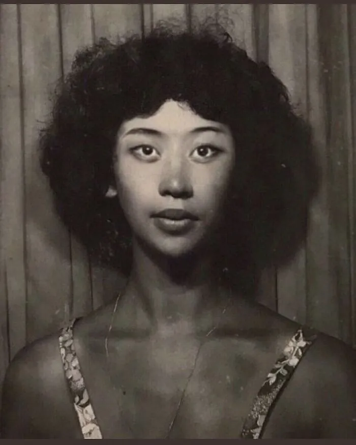 Vintage portrait of a woman with curly hair and patterned dress, showcasing historical fashion.