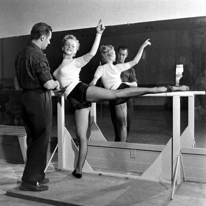 Ballet dancer practicing with an instructor in a historical photo, showcasing a captivating moment from the past.
