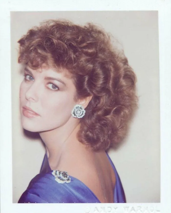 Young woman in a blue dress with floral earrings, captured in a vintage photograph for a historical collection.