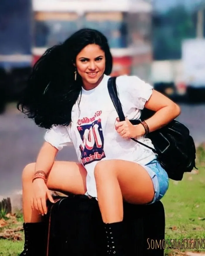Smiling woman sitting on a suitcase outdoors in a vintage t-shirt, capturing a historical vibe from the past.