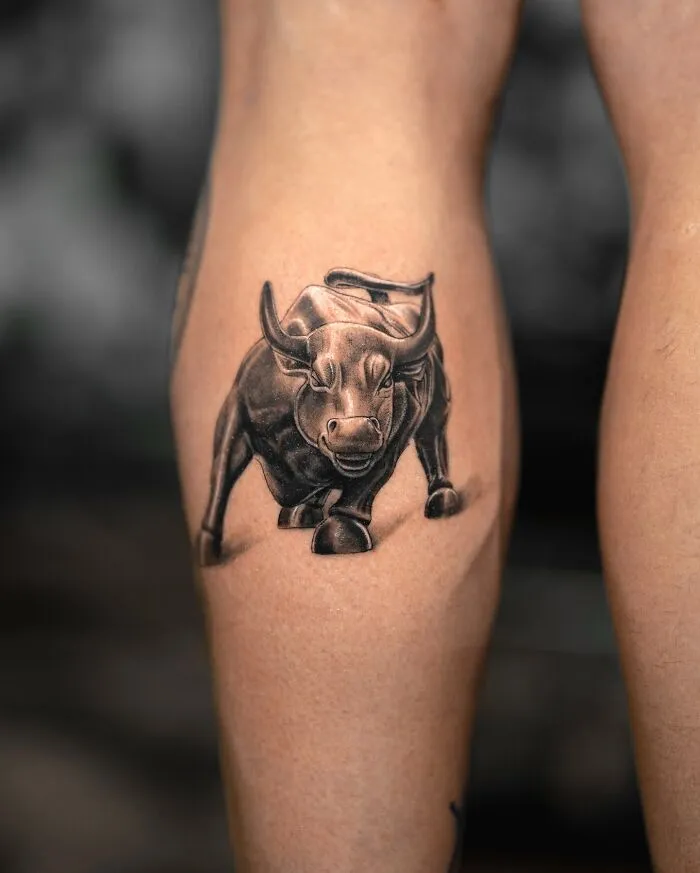 A lifelike bull tattoo by Tatu Panda on a person's calf, showcasing intricate detail and shading.