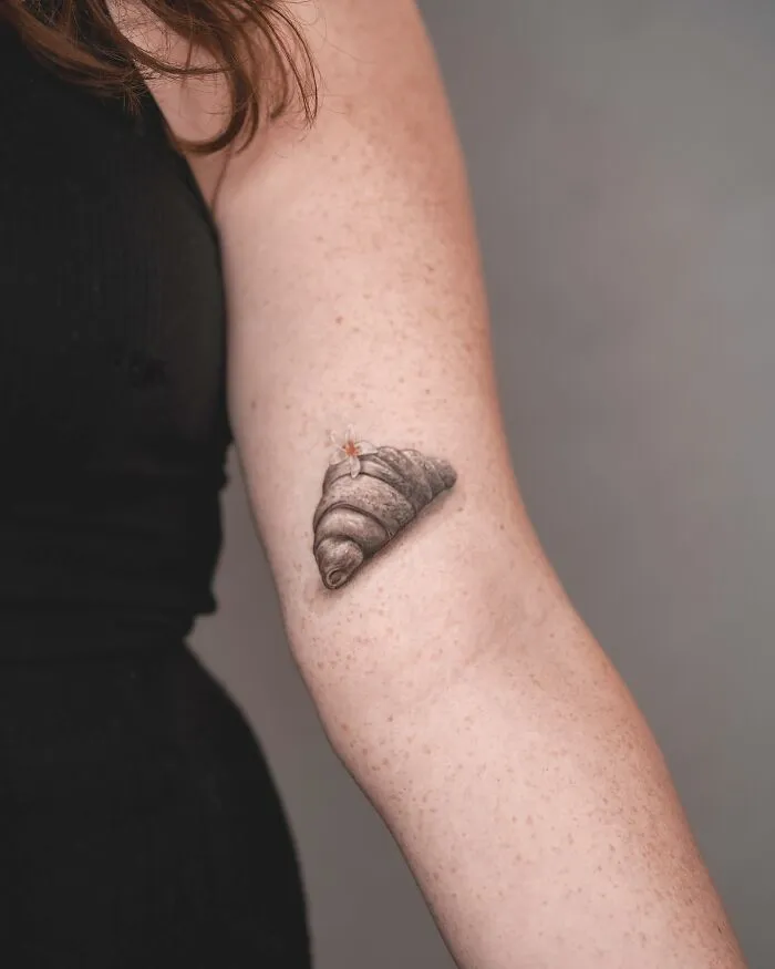 Lifelike shell tattoo by Tatu Panda on a person's forearm in a realistic 3D style.