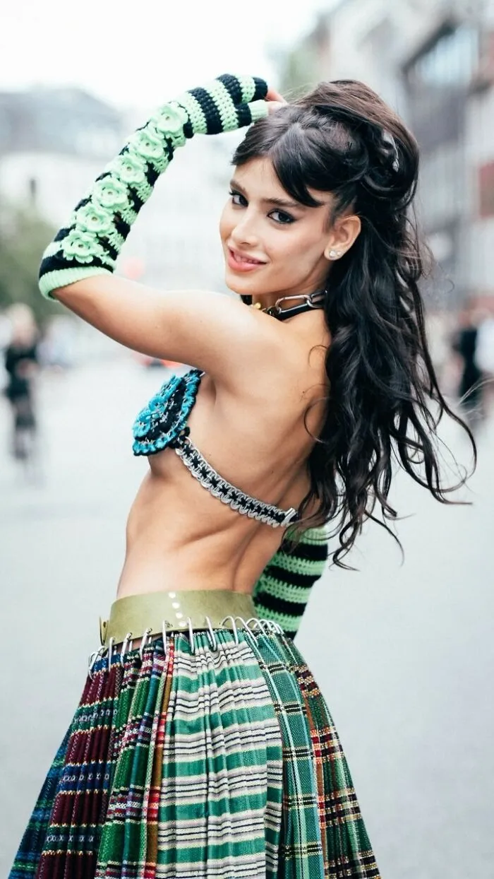 A visually striking street portrait of a smiling woman in a colorful outfit, turning back toward the camera.