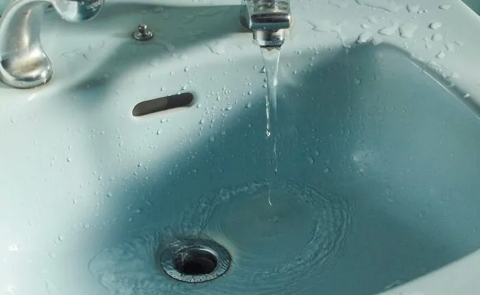Running water in a bathroom sink, highlighting the showering debate between night and morning routines.