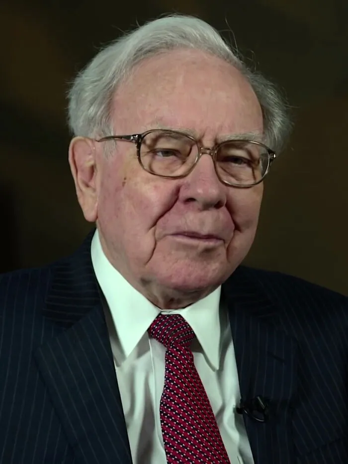 Elderly man in glasses, suit, and red tie, representing one of the richest people with wealth exceeding many countries.