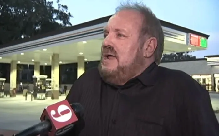 Man interviewed outside a Florida gas station for a news segment on unusual local events.
