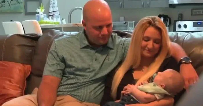 A Florida couple sitting on a couch, lovingly holding their baby in a cozy living room setting.