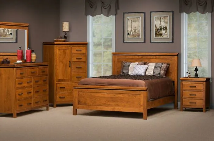 Dated wooden bedroom furniture set with dark bedding and gray walls.