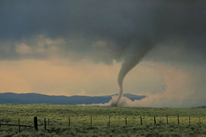 A tornado touches down in a vast field, illustrating random world facts and powerful natural events.