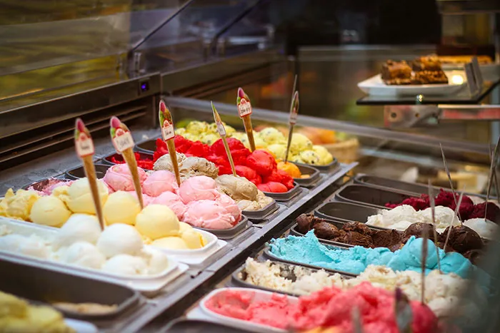 Restaurant kitchen display with colorful ice cream scoops in various flavors and trays.