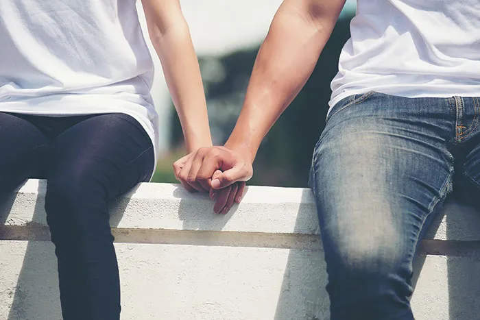 Two people in casual clothing holding hands, illustrating "just a friend" concept.