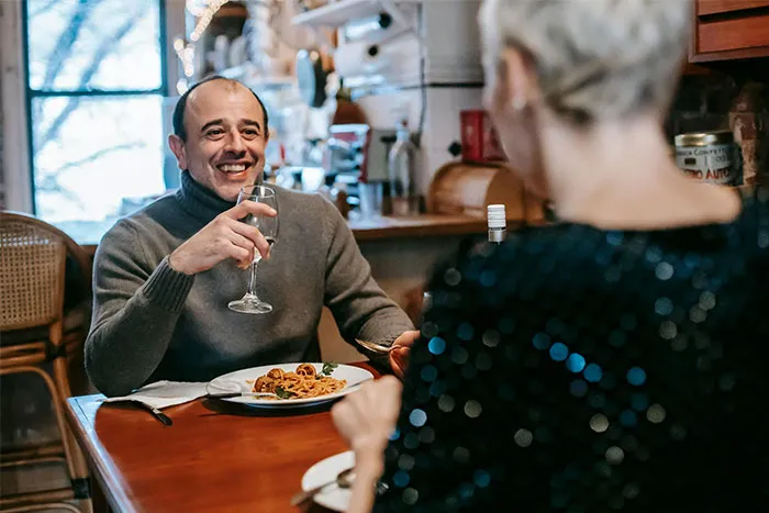A woman on a date with a man in a cozy restaurant setting, both enjoying a meal.