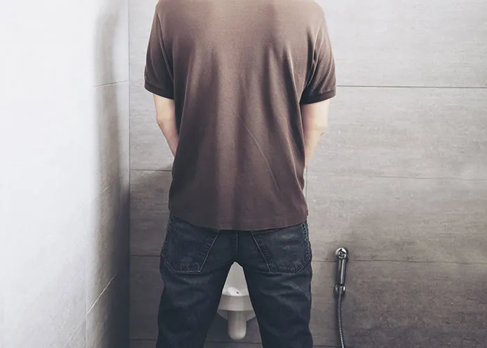 Man in casual wear standing in front of a urinal, reflecting common questions about men.