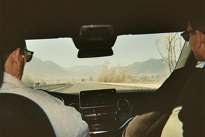 Two people driving on a mountain road, experiencing a crazy coincidence under clear skies.