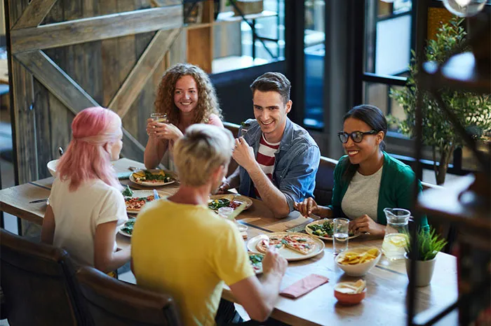 Group of friends sharing a meal in a cozy restaurant, laughing and enjoying coincidental stories.