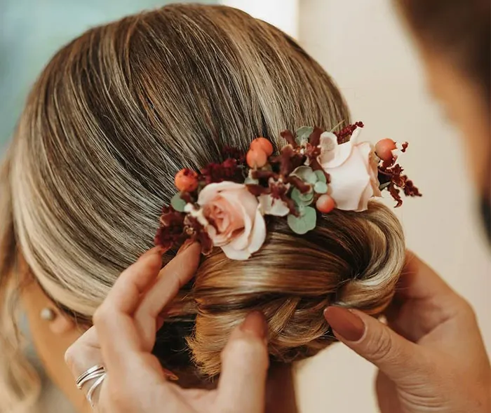 Bridesmaid hairstyle with floral hairpiece being adjusted for a wedding.
