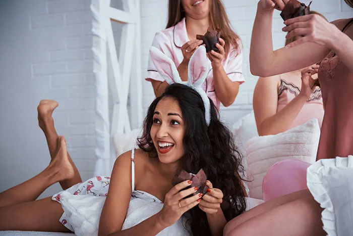 Women enjoying cupcakes in pajamas during a fun bridesmaid gathering.