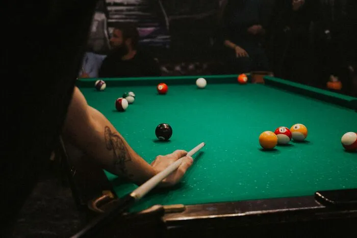 A person playing pool, using a cue stick on a green table with colorful balls, illustrating creative product use.