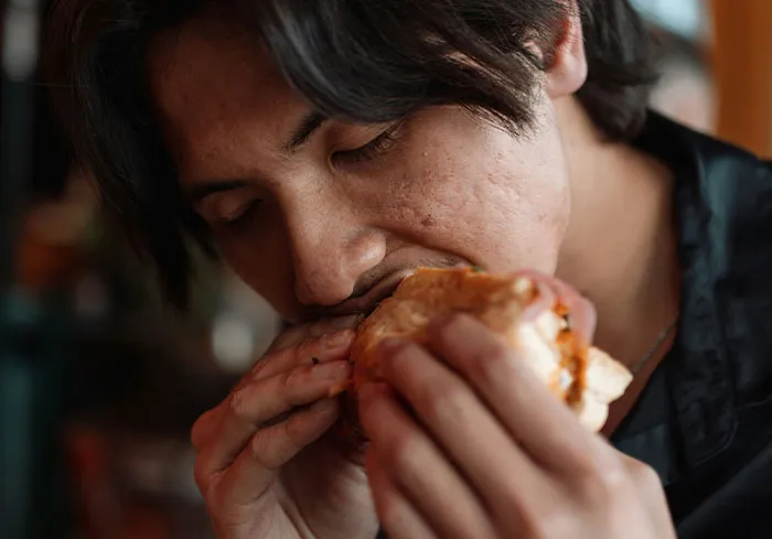 A person enjoying a sandwich, representing stress relief from bosses from hell.