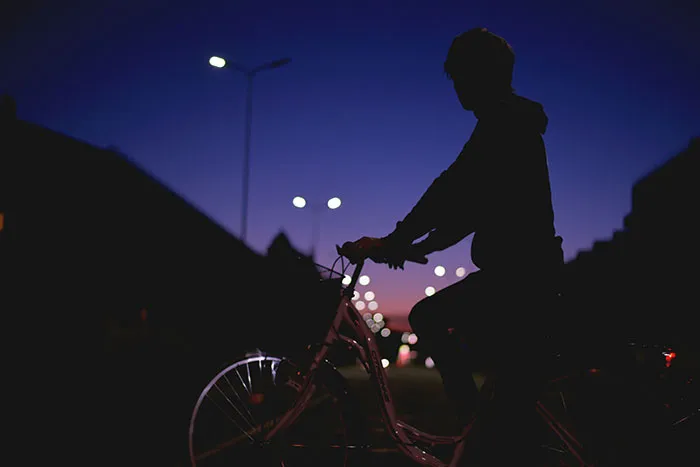 Silhouette of a person biking at night, city lights in the background, depicting life-saving split-second decisions.