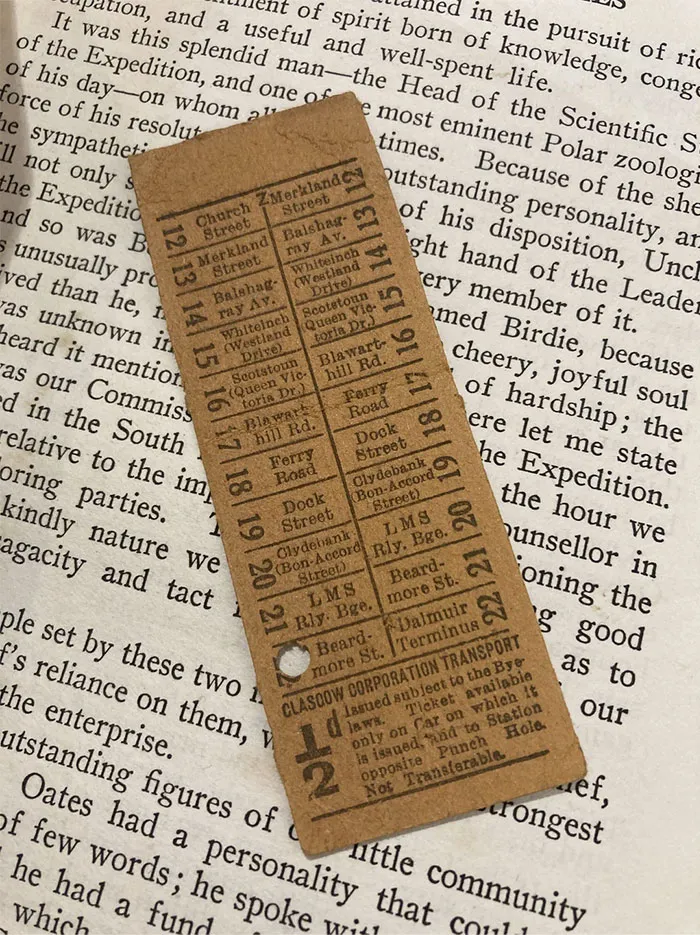 Vintage ticket bookmark on open book, showcasing a cool and unique find for book lovers.