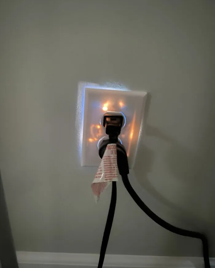Glowing outlet with a plug and a red tag, creating a cool and random visual effect on the wall.