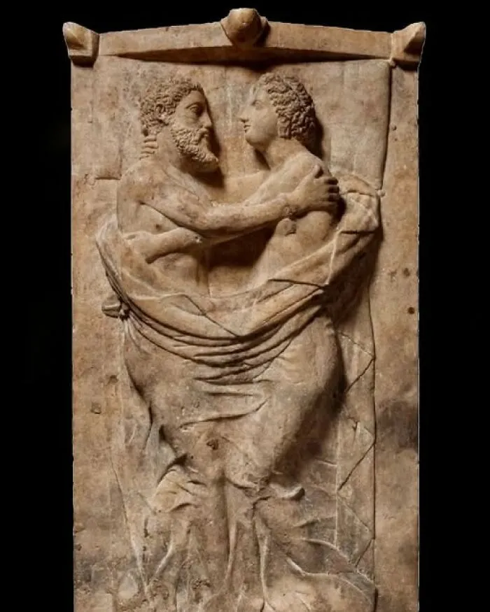 Ancient stone relief sculpture of two embracing figures, showcasing detailed craftsmanship in archaeology and architecture.
