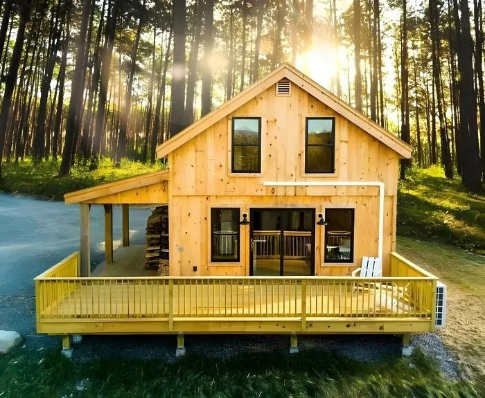 Modern wooden cabin with large deck surrounded by forest, showcasing impressive woodworking ideas and craftsmanship.