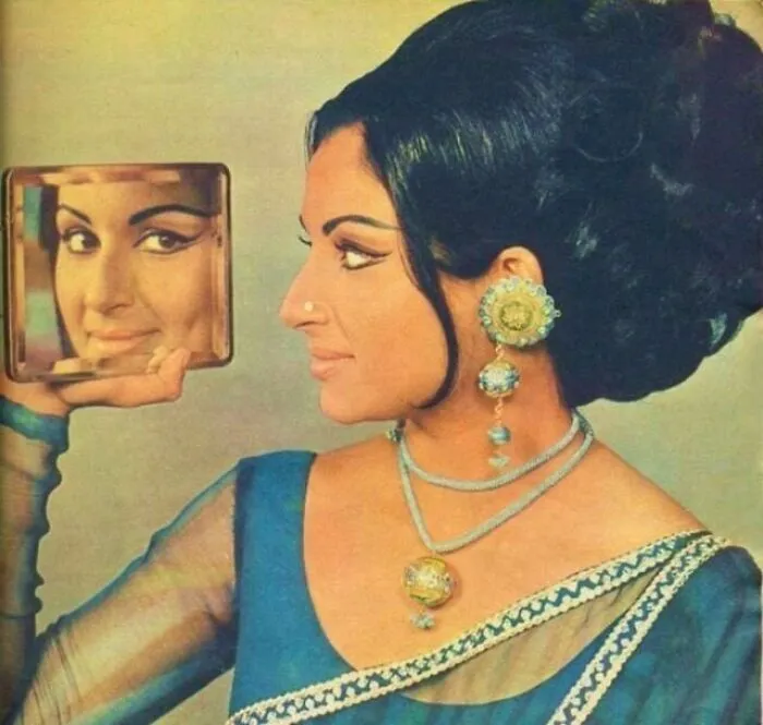 Vintage hairstyle with elaborate bun and mirror reflection, featuring traditional jewelry and saree.