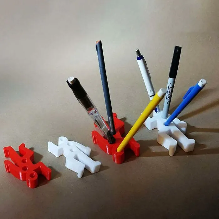 Pen holders shaped like figures, organizing work supplies on a desk.