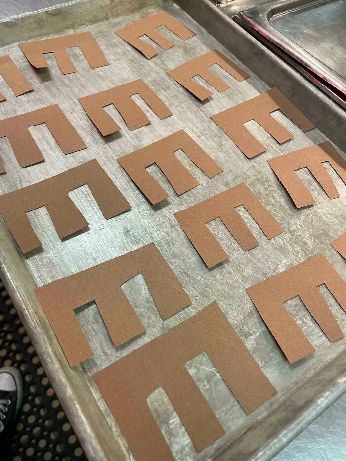 Brown paper E's arranged on a baking tray as a humorous prank by a creative coworker.