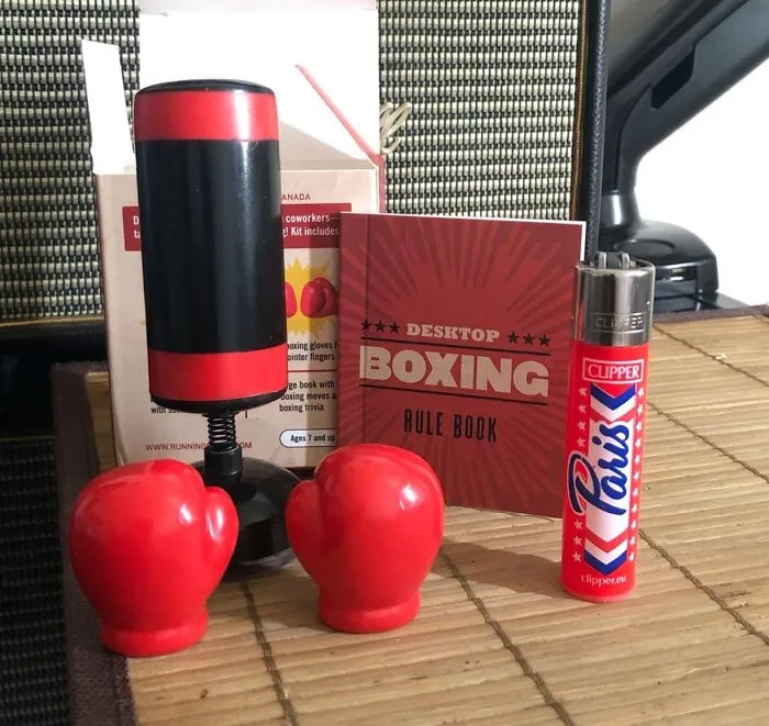 Desktop boxing set with gloves, punch bag, rule book, and a Clipper lighter, perfect work supplies for stress relief.