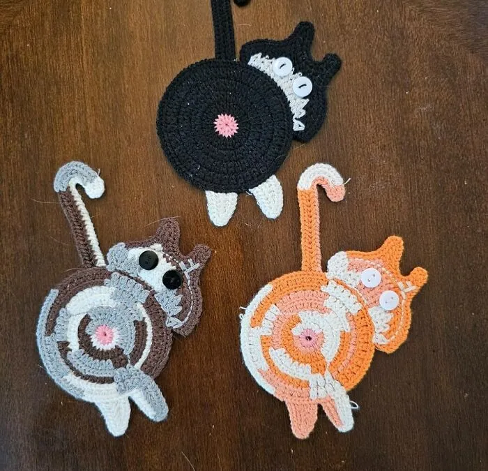 Crocheted cat coasters on a wooden table, ideal work supplies to brighten up Monday.