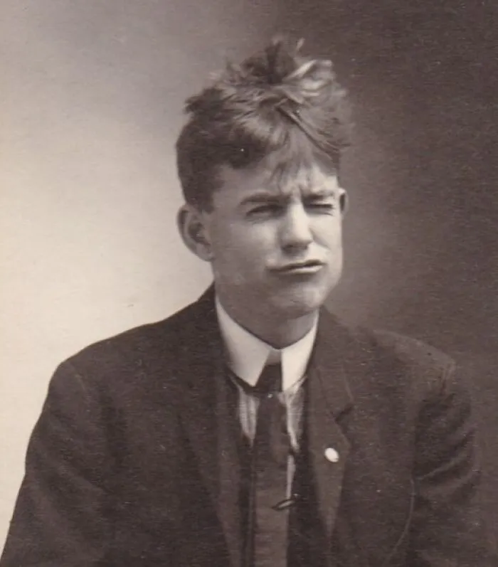 Vintage photo of a man with a quirky hairstyle, wearing a suit and making a playful face.