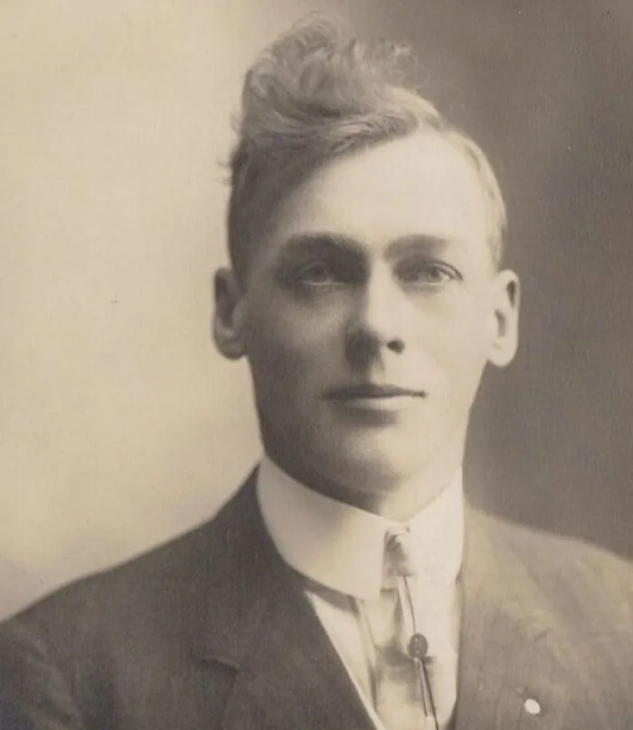 Vintage portrait of a man with an unusual hairstyle from yesteryear, wearing a suit and tie.