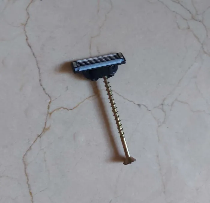 Cuchilla de afeitar improvisada con un tornillo para reparación fallida.