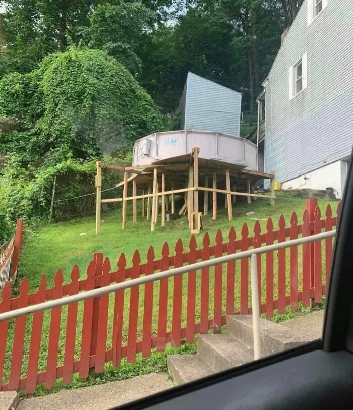 Piscina elevada de forma inestable sobre soporte de madera, intento de reparación fallido.