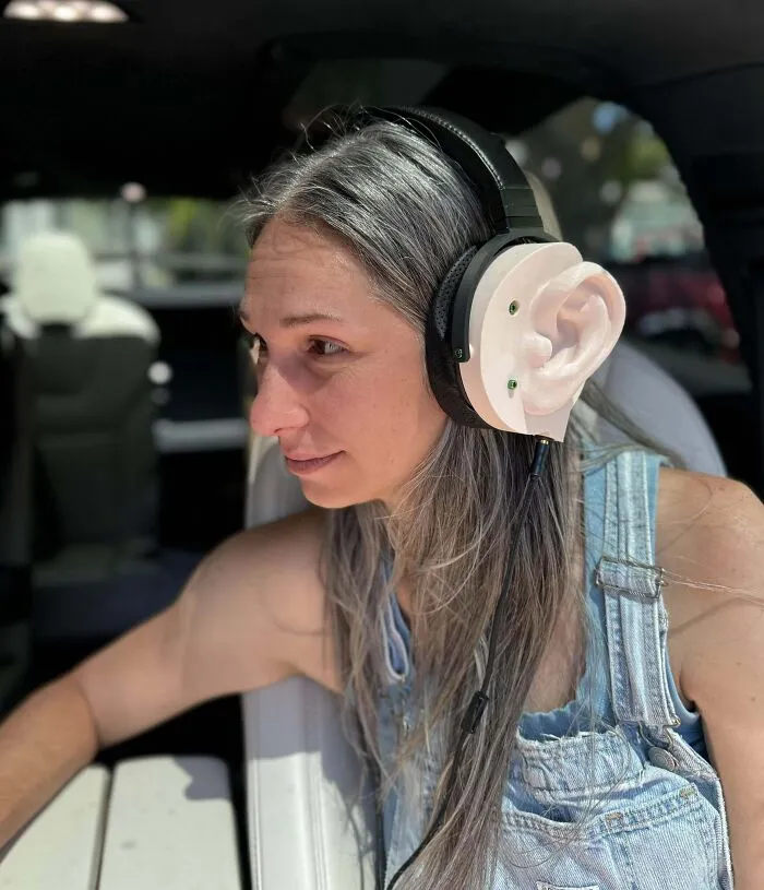 Mujer con auriculares creativos de oreja grande, reflejo del humor de novios divertidos.