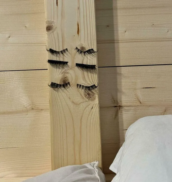 Pestañas en un tablón de madera con nudos parecidos a un rostro, ejemplificando cómo los novios divertidos hacen reír.